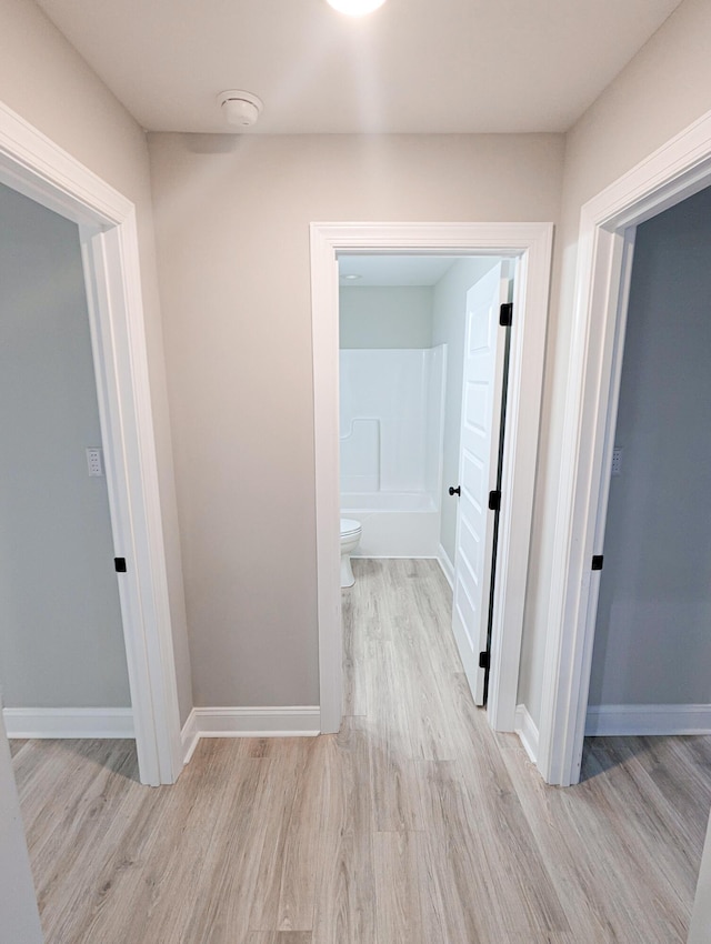 corridor featuring wood finished floors and baseboards