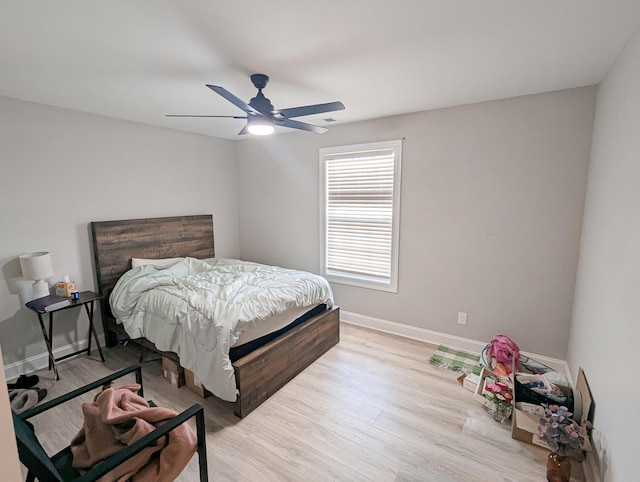 bedroom featuring visible vents, baseboards, light wood-type flooring, and ceiling fan