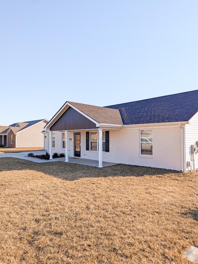 ranch-style home featuring a shingled roof and a front lawn