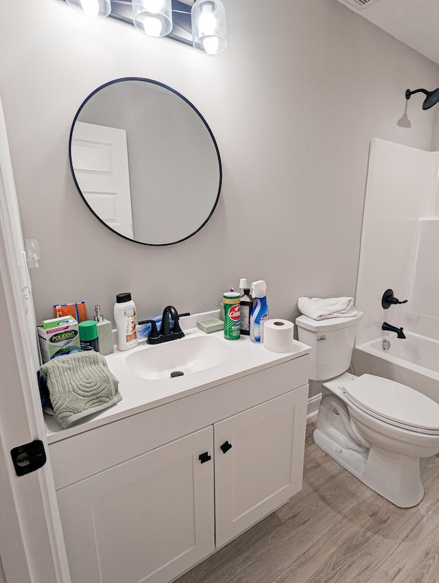 bathroom with vanity, washtub / shower combination, toilet, and wood finished floors