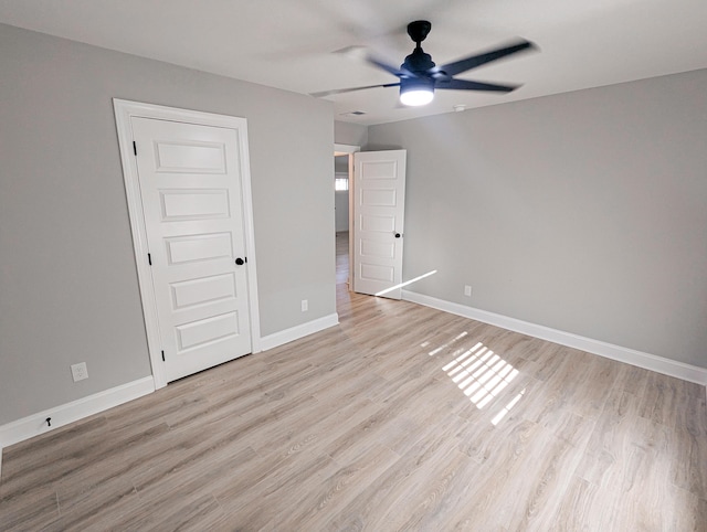 unfurnished bedroom featuring light wood-style flooring, a ceiling fan, and baseboards