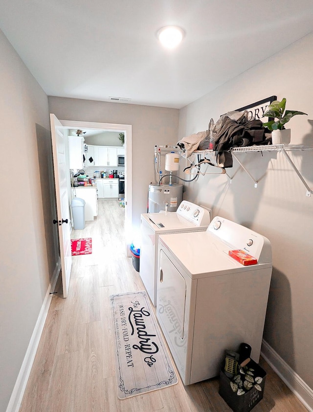 laundry room with washing machine and clothes dryer, laundry area, light wood-type flooring, and baseboards