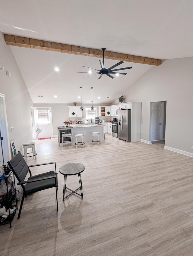 living area featuring light wood finished floors, vaulted ceiling with beams, baseboards, recessed lighting, and a ceiling fan