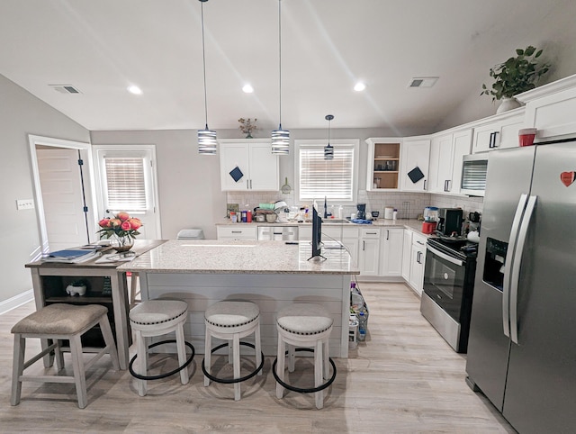 kitchen with visible vents, backsplash, appliances with stainless steel finishes, and lofted ceiling