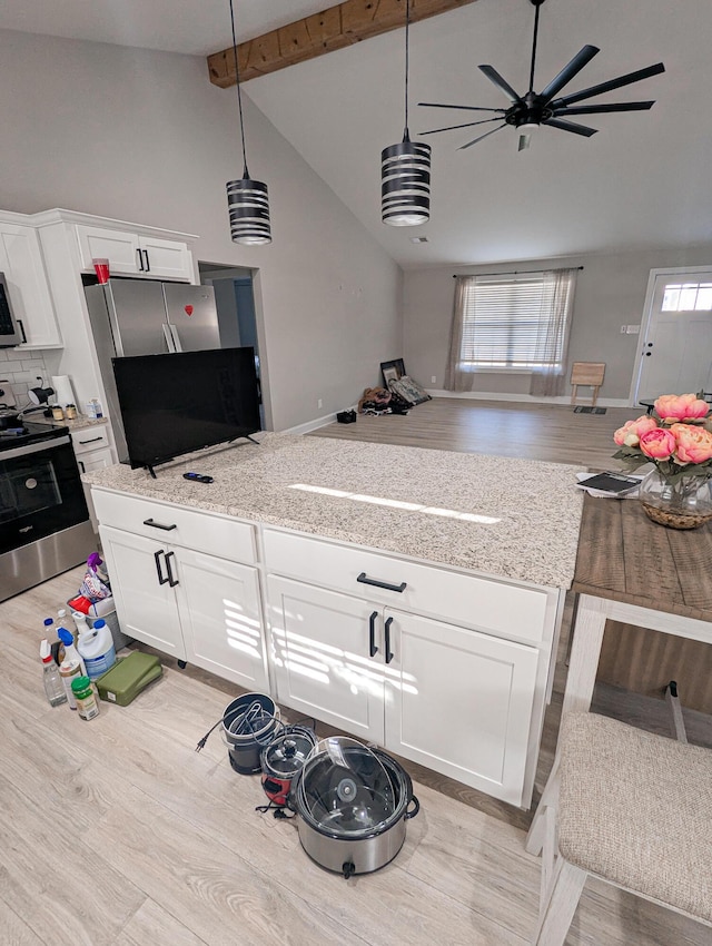 kitchen with light wood finished floors, open floor plan, appliances with stainless steel finishes, white cabinets, and high vaulted ceiling