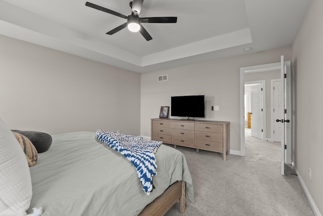 bedroom featuring visible vents, light carpet, a ceiling fan, a tray ceiling, and baseboards