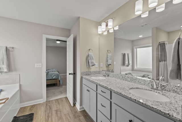 full bathroom featuring a sink, visible vents, wood finished floors, and a bath