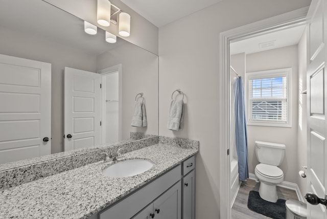 bathroom with vanity, wood finished floors, baseboards, shower / bath combo with shower curtain, and toilet