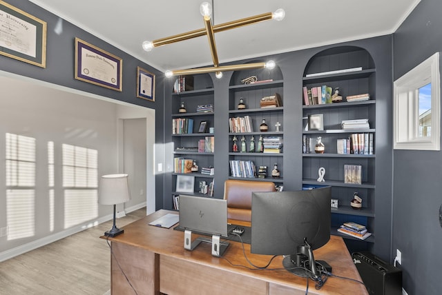 office space with ornamental molding, built in shelves, baseboards, and wood finished floors