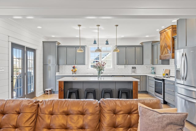 kitchen featuring open floor plan, light countertops, a wealth of natural light, gray cabinets, and appliances with stainless steel finishes