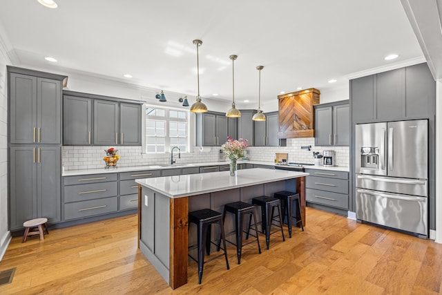 kitchen featuring custom range hood, a breakfast bar, stainless steel refrigerator with ice dispenser, and ornamental molding