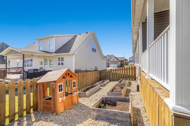 back of house with a vegetable garden, fence, and roof with shingles