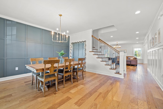 dining area featuring light wood finished floors, stairs, ornamental molding, an inviting chandelier, and a decorative wall