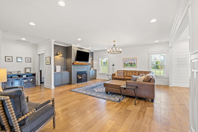 living room with baseboards, a fireplace with flush hearth, recessed lighting, ornamental molding, and light wood-type flooring