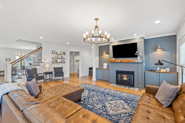 living room featuring a fireplace with flush hearth, recessed lighting, ornamental molding, stairs, and light wood-style floors