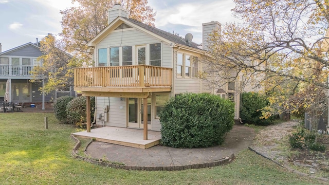 rear view of house with a wooden deck, a lawn, and a chimney