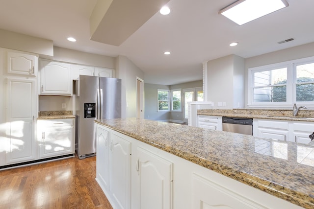 kitchen with visible vents, appliances with stainless steel finishes, wood finished floors, white cabinetry, and a sink