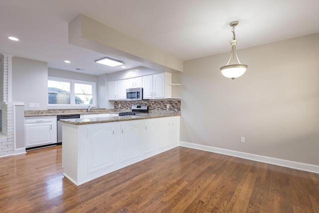 kitchen featuring dark wood-style floors, a peninsula, decorative backsplash, appliances with stainless steel finishes, and white cabinetry