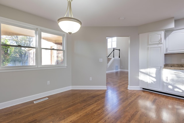 unfurnished dining area featuring visible vents, baseboards, plenty of natural light, and dark wood finished floors