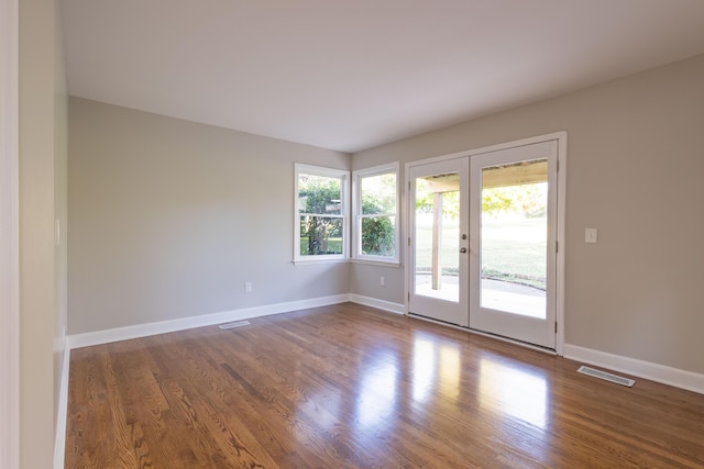 spare room featuring visible vents, baseboards, and wood finished floors