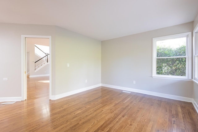 spare room with stairway, visible vents, baseboards, and light wood finished floors