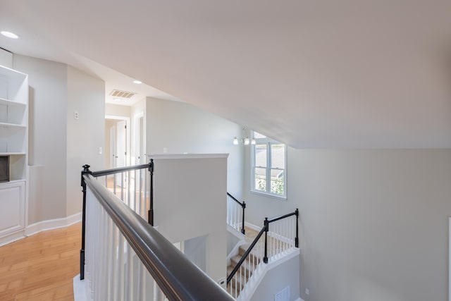 corridor featuring visible vents, light wood finished floors, baseboards, recessed lighting, and an upstairs landing