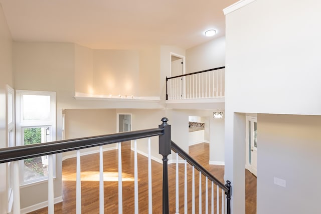 staircase with baseboards, a towering ceiling, and wood finished floors