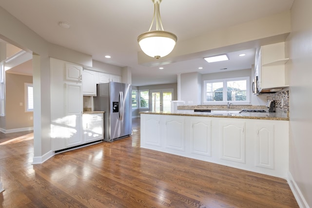 kitchen featuring stainless steel appliances, a peninsula, white cabinets, a healthy amount of sunlight, and dark wood-style flooring