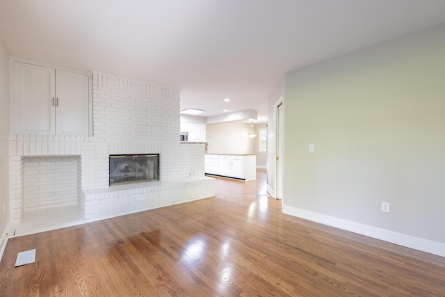 unfurnished living room with light wood-type flooring, baseboards, visible vents, and a fireplace