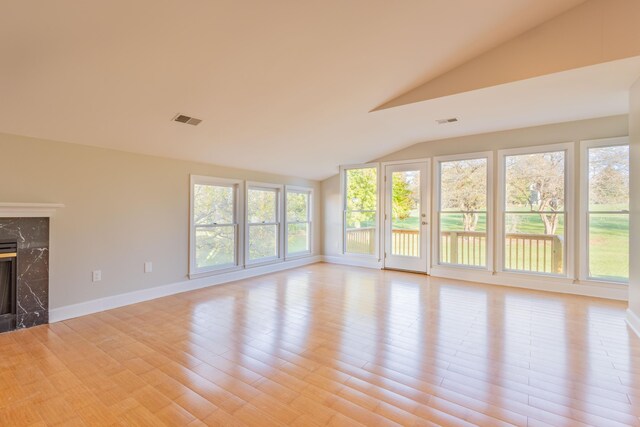 unfurnished living room with light wood-type flooring, baseboards, visible vents, and a fireplace