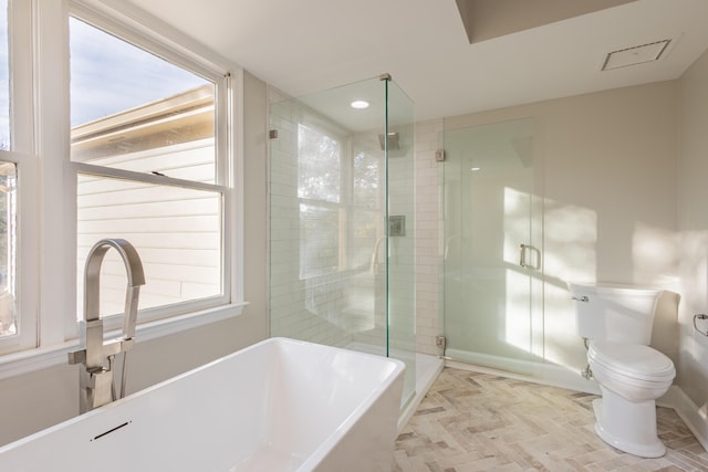 bathroom with toilet, a stall shower, a sink, baseboards, and a freestanding bath