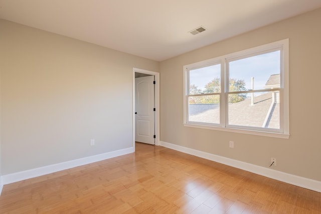 spare room featuring visible vents, baseboards, and light wood finished floors