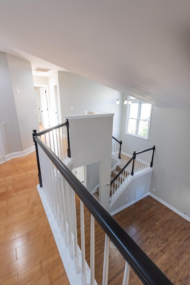 staircase with wood finished floors, visible vents, and baseboards