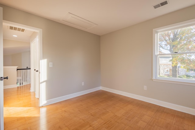 empty room with baseboards, visible vents, and light wood finished floors