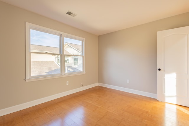 spare room featuring visible vents, baseboards, and light wood finished floors