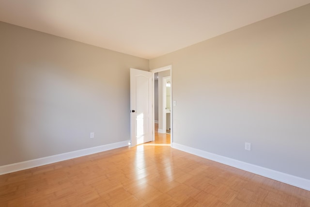 spare room with baseboards and light wood-type flooring