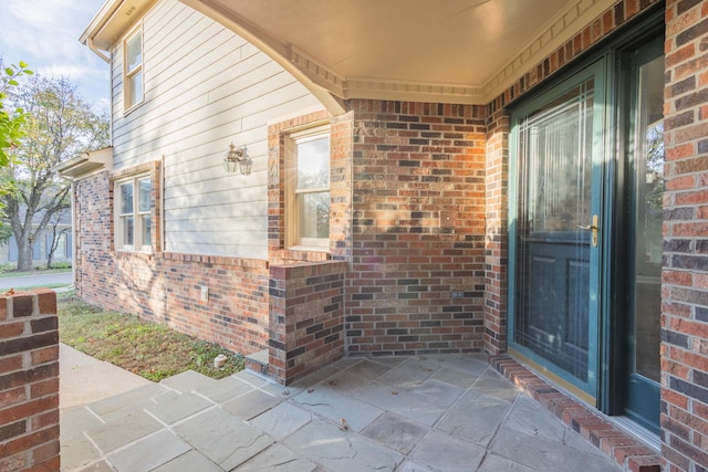 property entrance with brick siding and a patio area