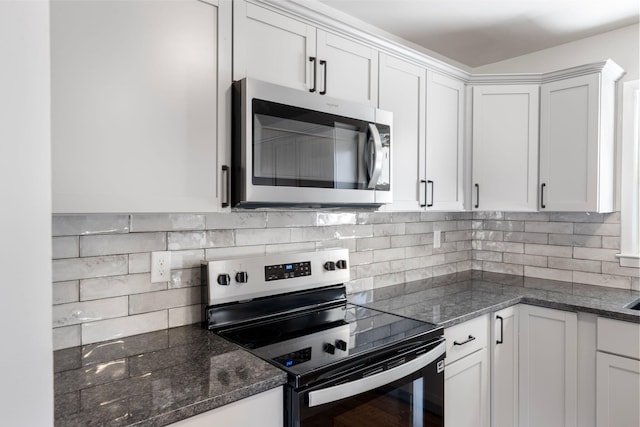 kitchen with white cabinetry, decorative backsplash, dark stone counters, and stainless steel appliances