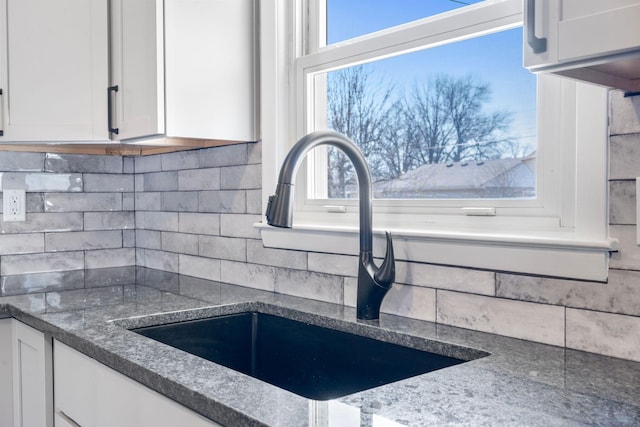 room details with white cabinetry, backsplash, and a sink