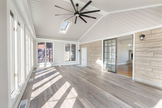 unfurnished sunroom with visible vents, vaulted ceiling with skylight, and ceiling fan