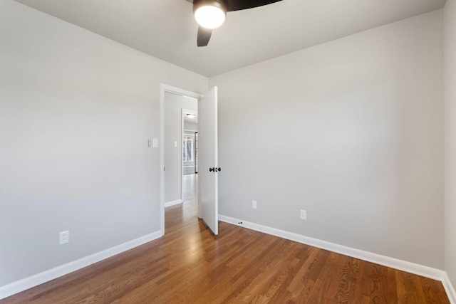 empty room with a ceiling fan, wood finished floors, and baseboards