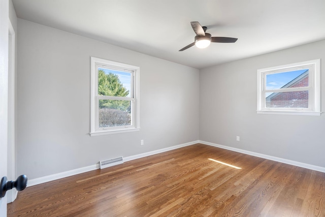 unfurnished room with wood finished floors, baseboards, visible vents, and ceiling fan