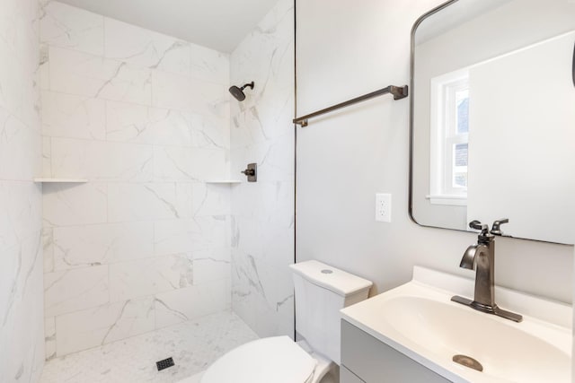 bathroom featuring a tile shower, toilet, and vanity