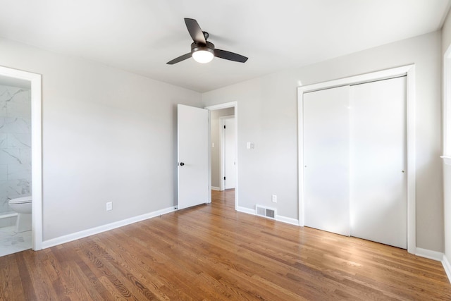 unfurnished bedroom featuring visible vents, ensuite bathroom, wood finished floors, a closet, and baseboards