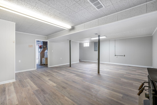 below grade area with electric panel, visible vents, baseboards, and wood finished floors