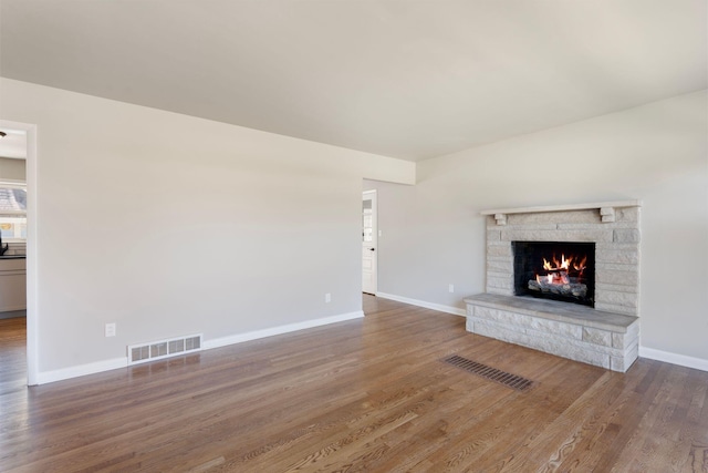 unfurnished living room featuring wood finished floors, visible vents, and baseboards