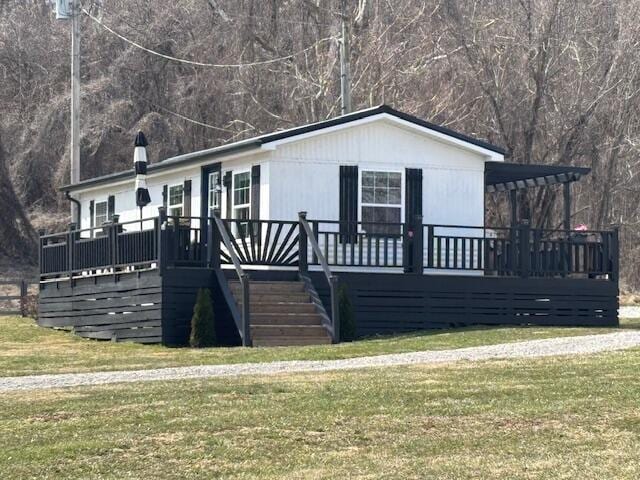 view of front facade with a wooden deck, stairs, and a front yard