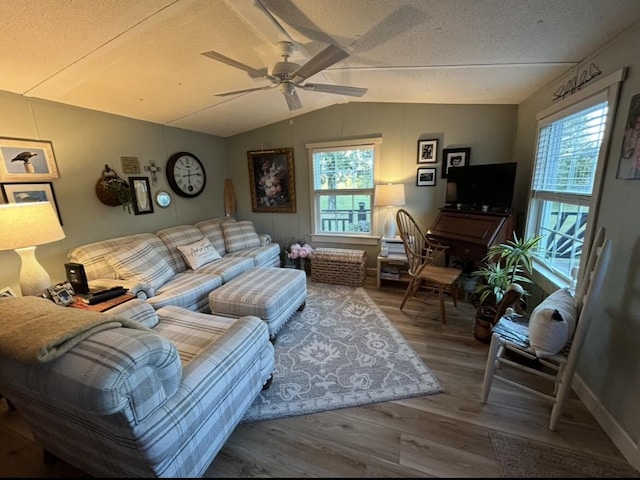 living room featuring baseboards, ceiling fan, lofted ceiling, wood finished floors, and a textured ceiling