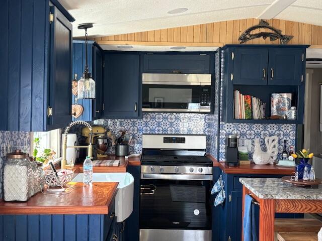 kitchen featuring blue cabinetry, appliances with stainless steel finishes, and wood walls