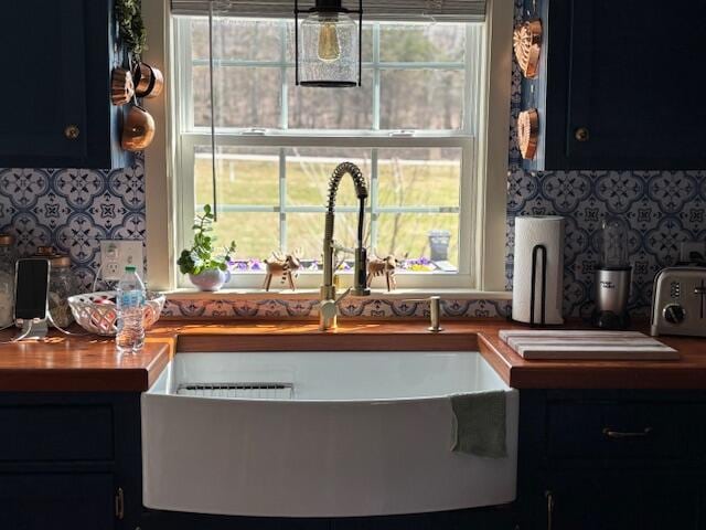 kitchen featuring a toaster, backsplash, dark cabinetry, and a sink